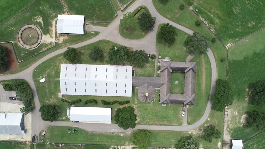 The improved core of the ranch seen from directly overhead — covered arena, stable complex, residence and pastures