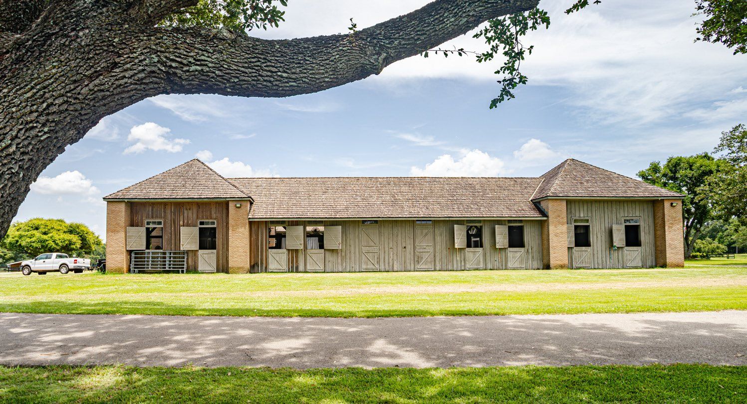 The primary stable complex seen from the internal ranch road beneath a live oak